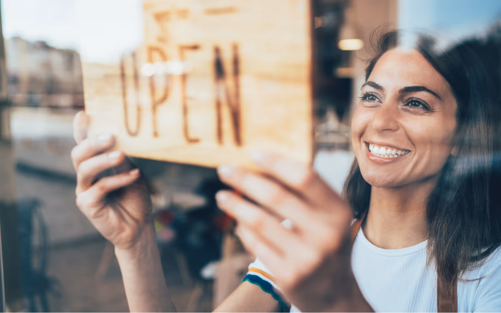 Woman smiling putting an 'Open' sign on a window